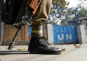 An Indian policeman guards the main gate of the United Nations Military Observer Group in Indian and Pakistan (UNMOGIP) office during a curfew in Srinagar